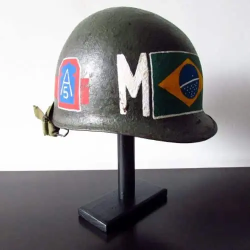 Capacete militar verde com a bandeira do Brasil, a letra M e uma insígnia no lado