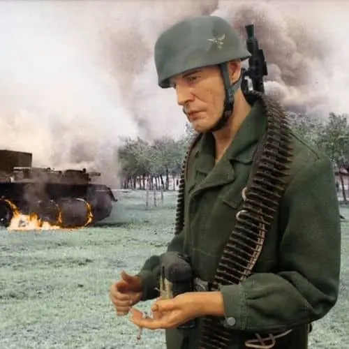 Figura de um soldado de capacete verde e cinto de munição, com um tanque em chamas ao fundo